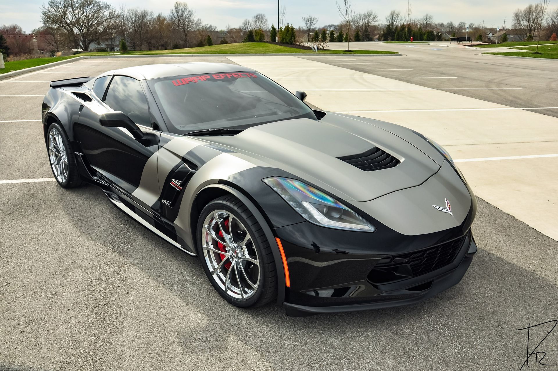 Black sports car parked on a road, with silver racing stripes and red accents.