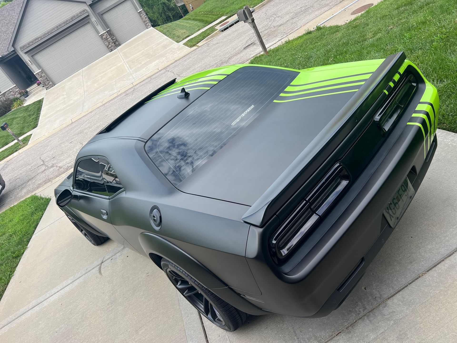 Black and lime-green sports car seen from the rear in a driveway