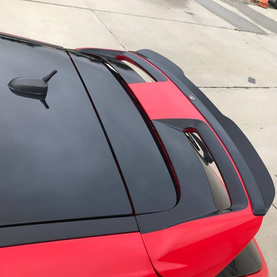 Red sports car rear spoiler and roof, black and bright red body panels parked outdoors