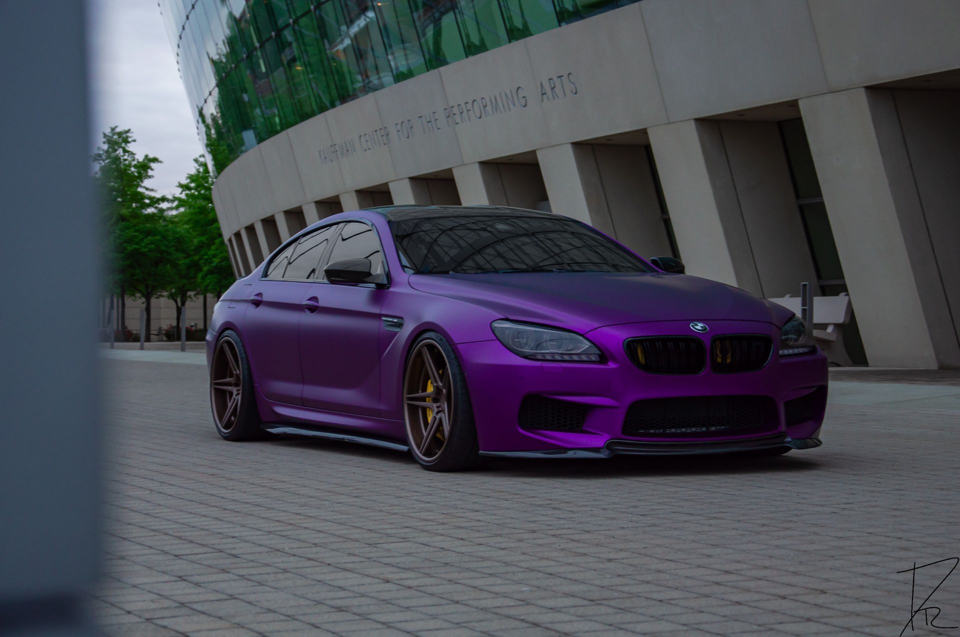 Purple sports car parked beside a modern building on a paved street