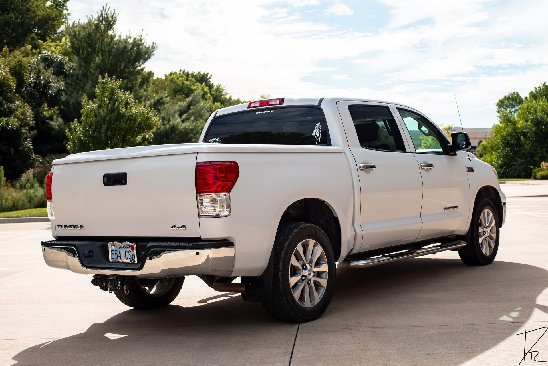 White pickup truck parked on a sunny driveway with trees in the background