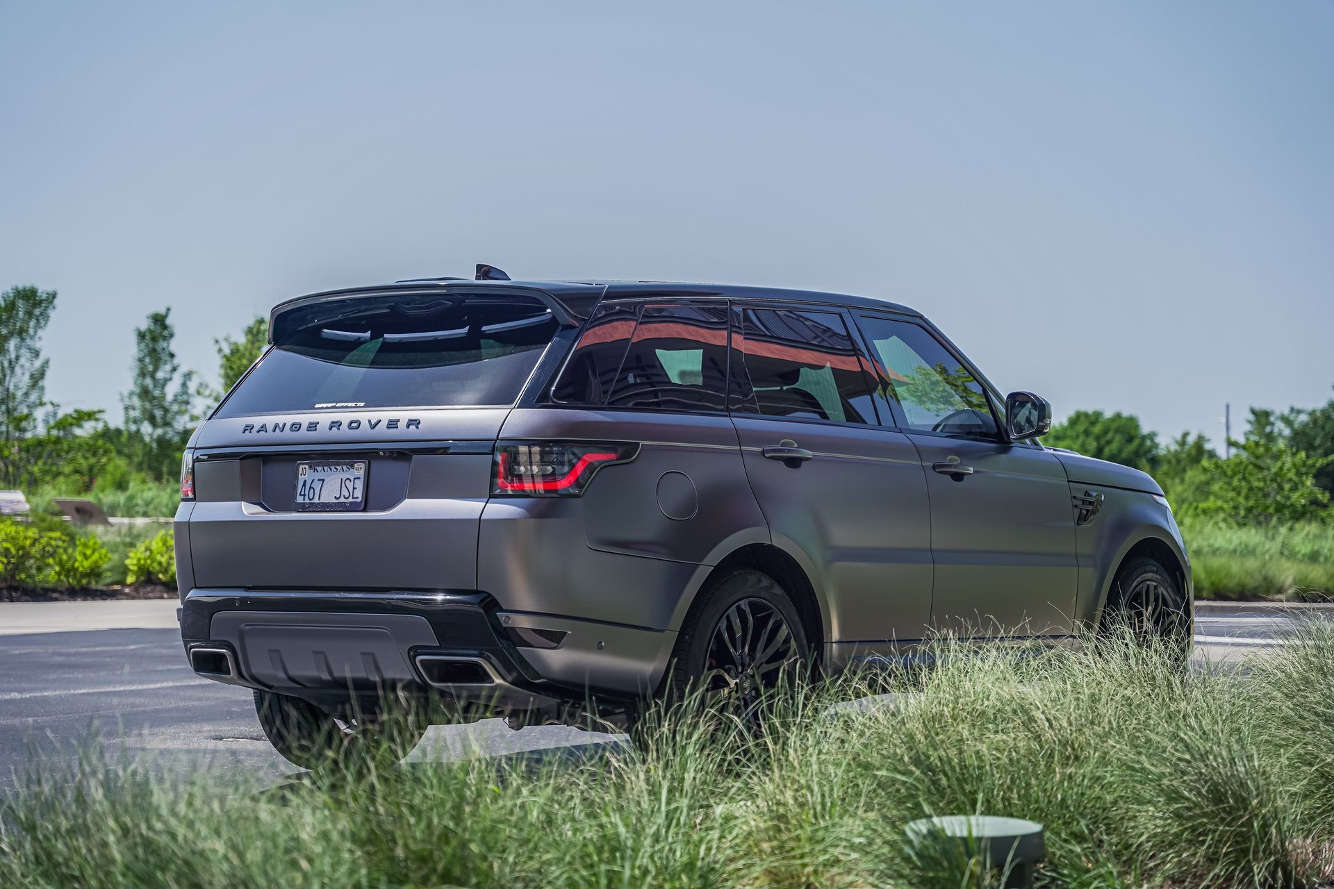 Dark gray SUV parked on a roadside with grass and trees under a clear sky