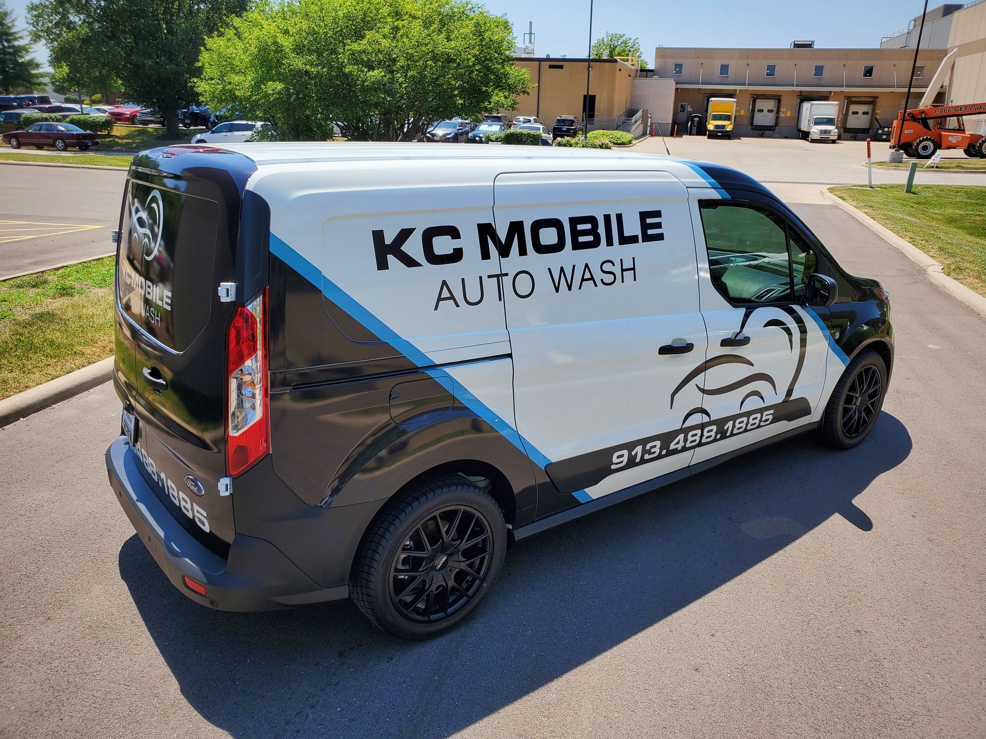 KC Mobile Auto Wash van parked on a sunny street, white and black with logo graphics.