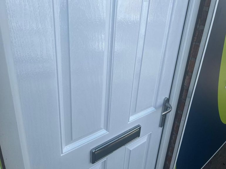 Close-up of the same door panels after spraying white, with the letterplate masked clean
