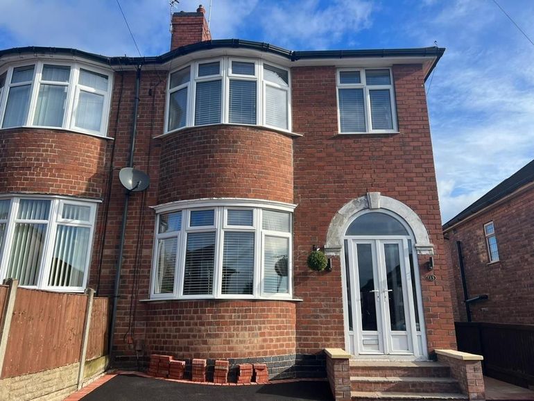 Bay-fronted red-brick semi with white uPVC windows and an arched door before spraying
