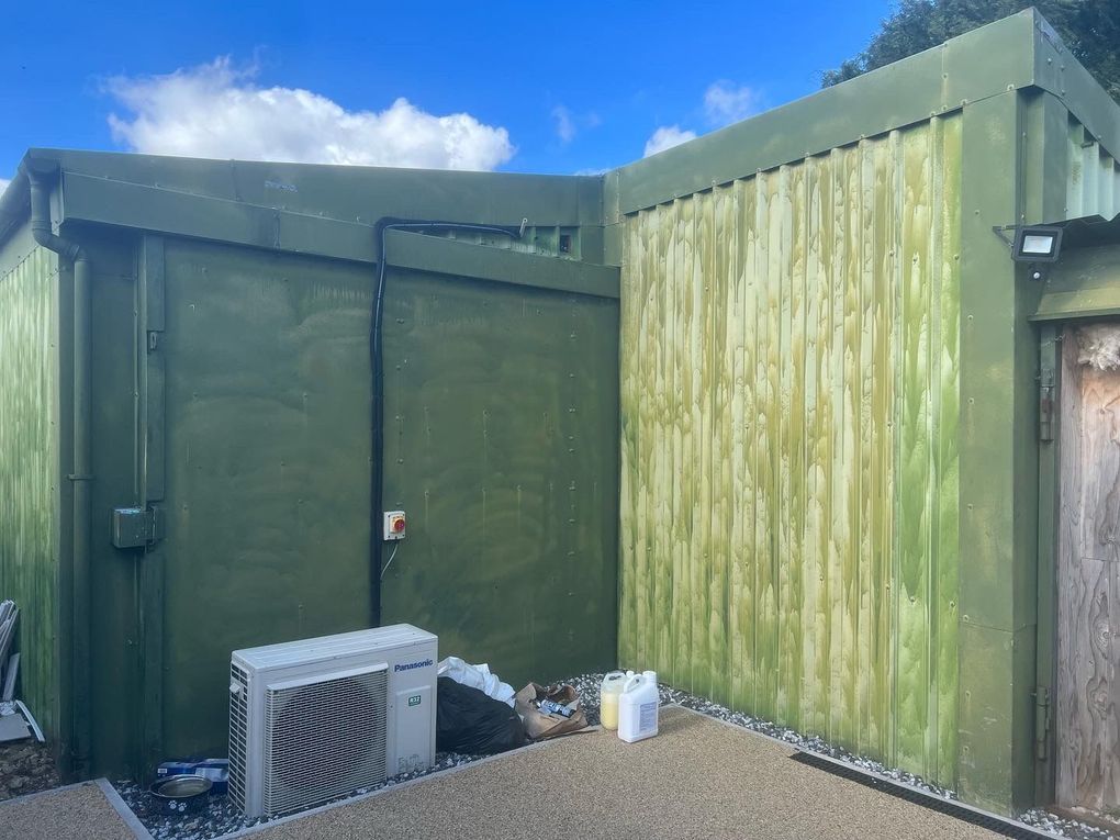 Commercial unit with weathered, streaked green metal cladding before respraying