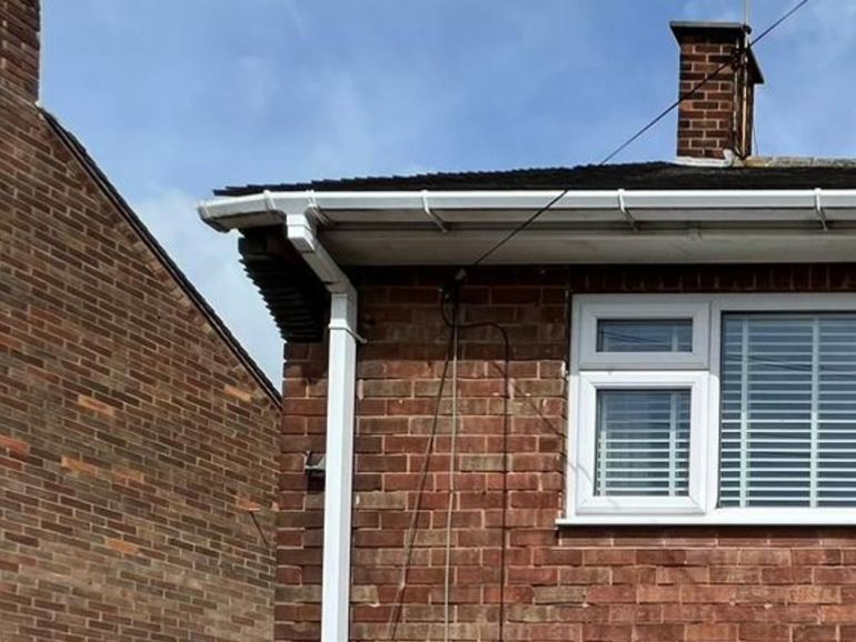 White fascia, soffit, gutter, downpipe and window on a brick house in Nottingham before spraying
