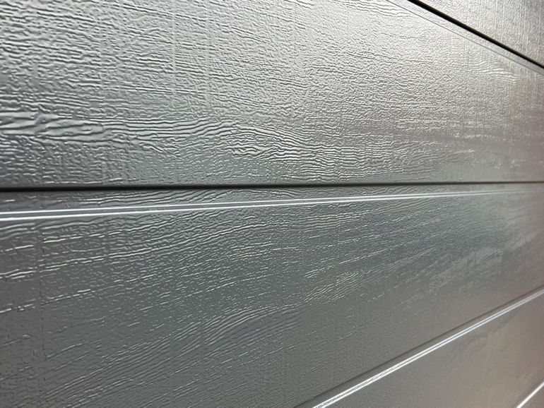Close-up of a sprayed garage door showing the woodgrain texture through the finish