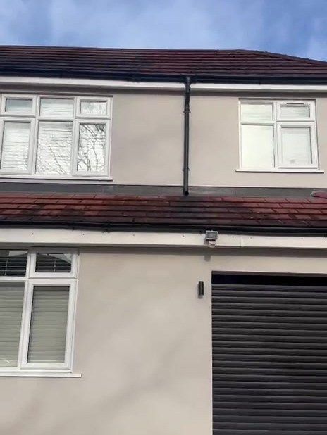 Detached house in Loughborough with white uPVC windows and a black roller garage door before spraying