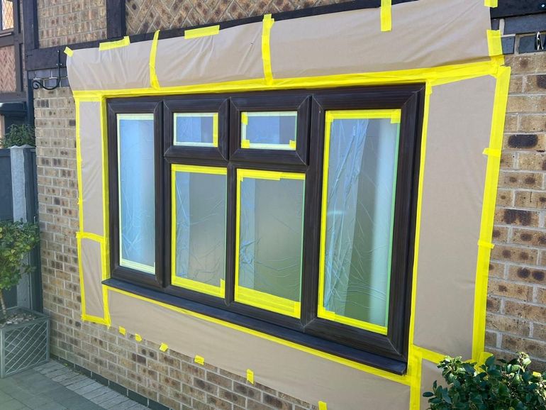 Brown uPVC window in Wollaton masked tight to the glass and sheeted before spraying