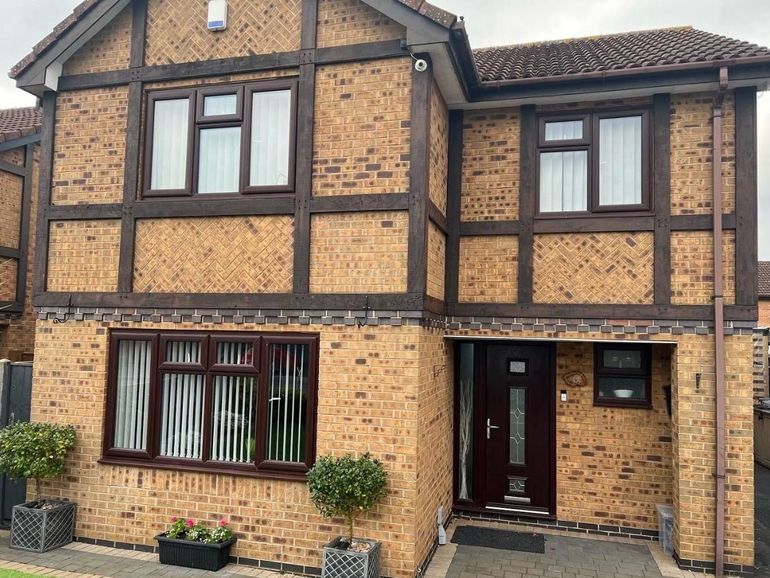 Detached house with dark brown uPVC windows and front door before spraying