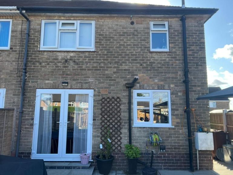 Rear of a brick semi with white uPVC windows and French doors before spraying