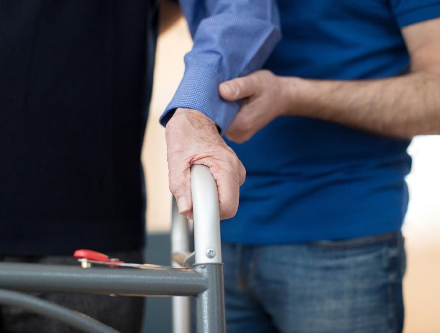  Senior man receiving mobility assistance from a caregiver, ensuring safe and independent living at home.
