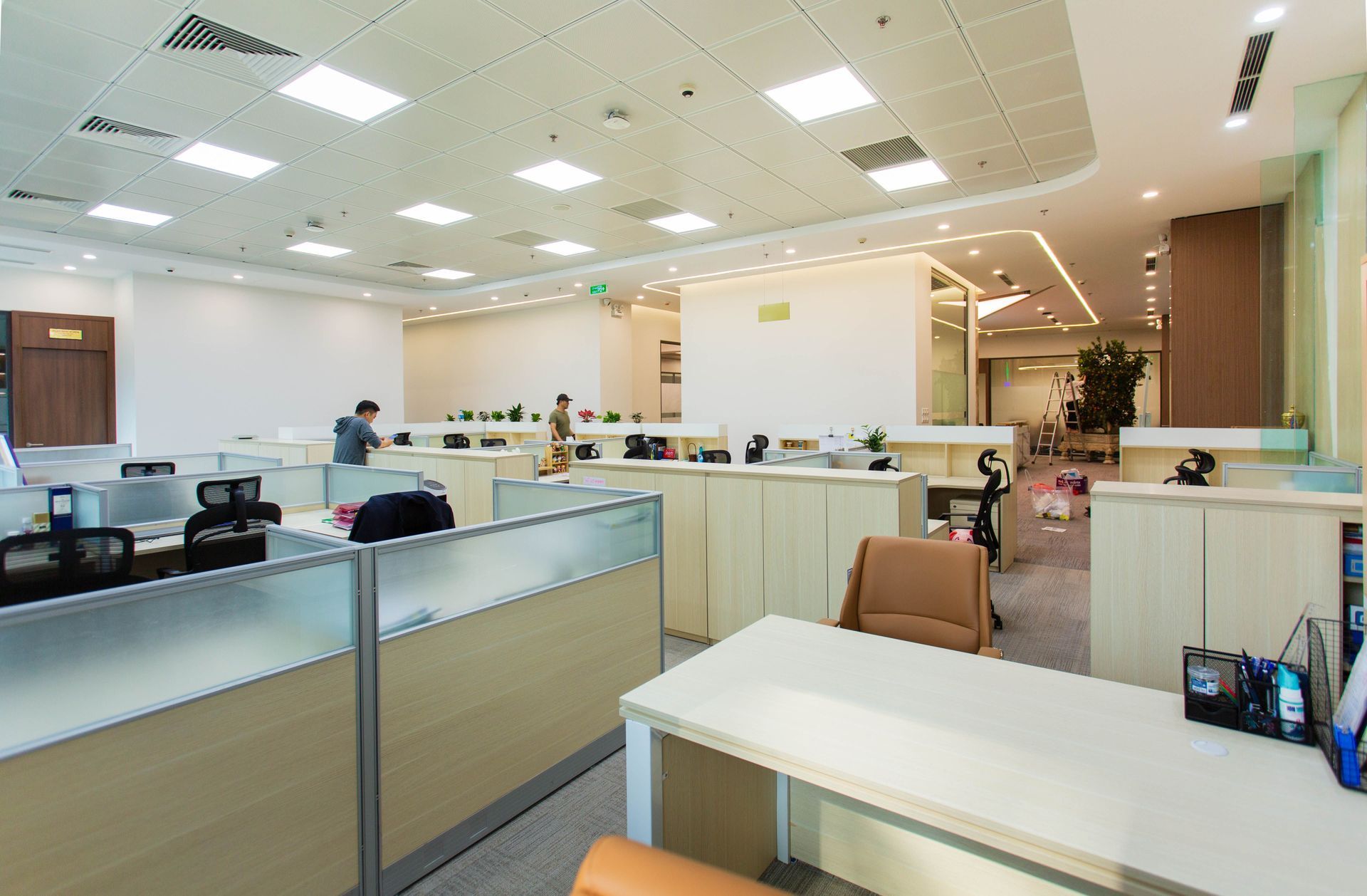 Open office workspace with cubicles, desks, chairs, and bright ceiling lights