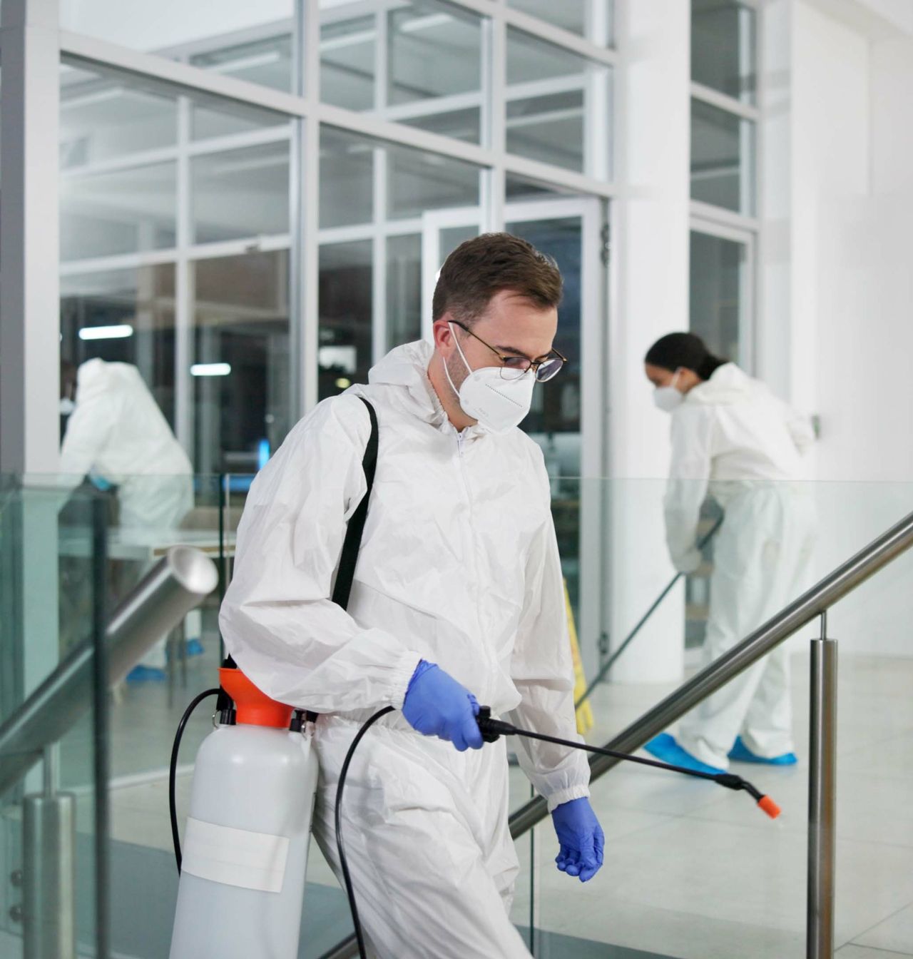 A man wearing a mask is spraying a staircase with a sprayer