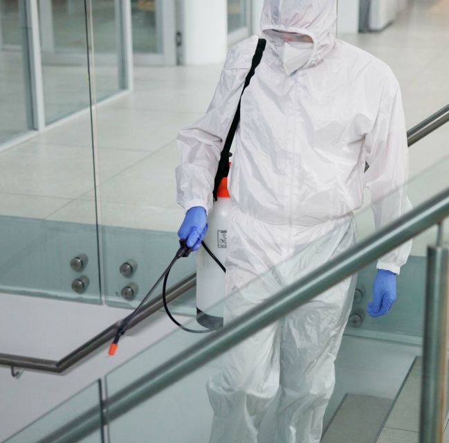 A man in a protective suit is spraying something with a sprayer