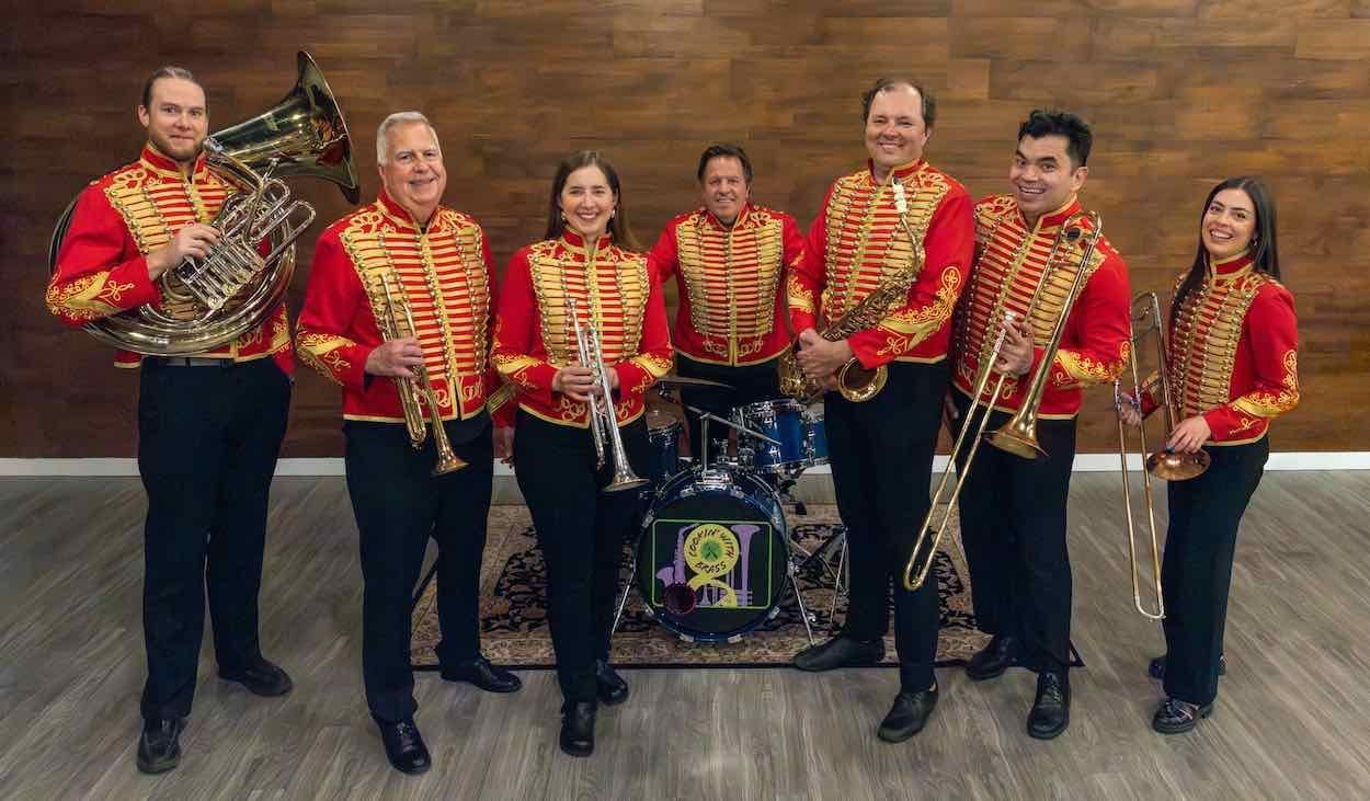 Six people in red-and-gold band uniforms posing with instruments in a studio