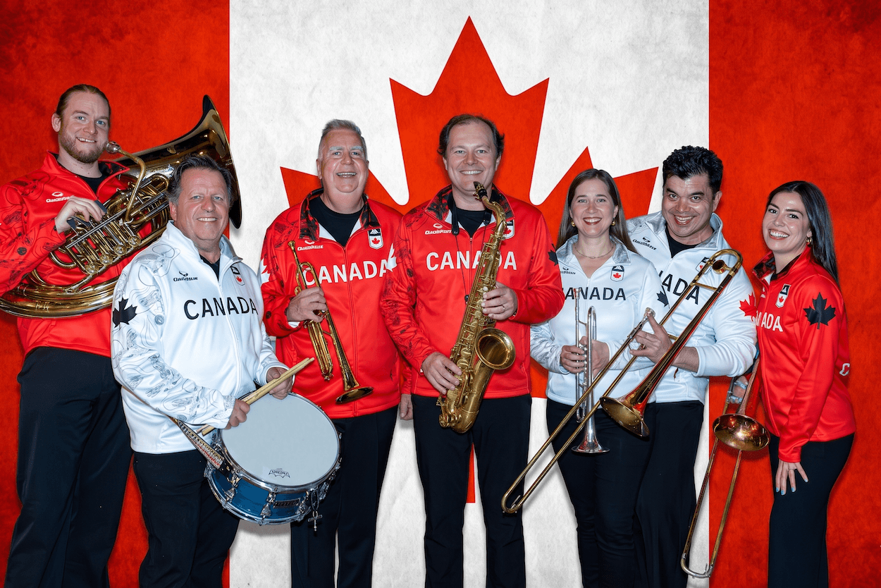 Canadian musicians posing with instruments in front of a red-and-white Canada flag backdrop.