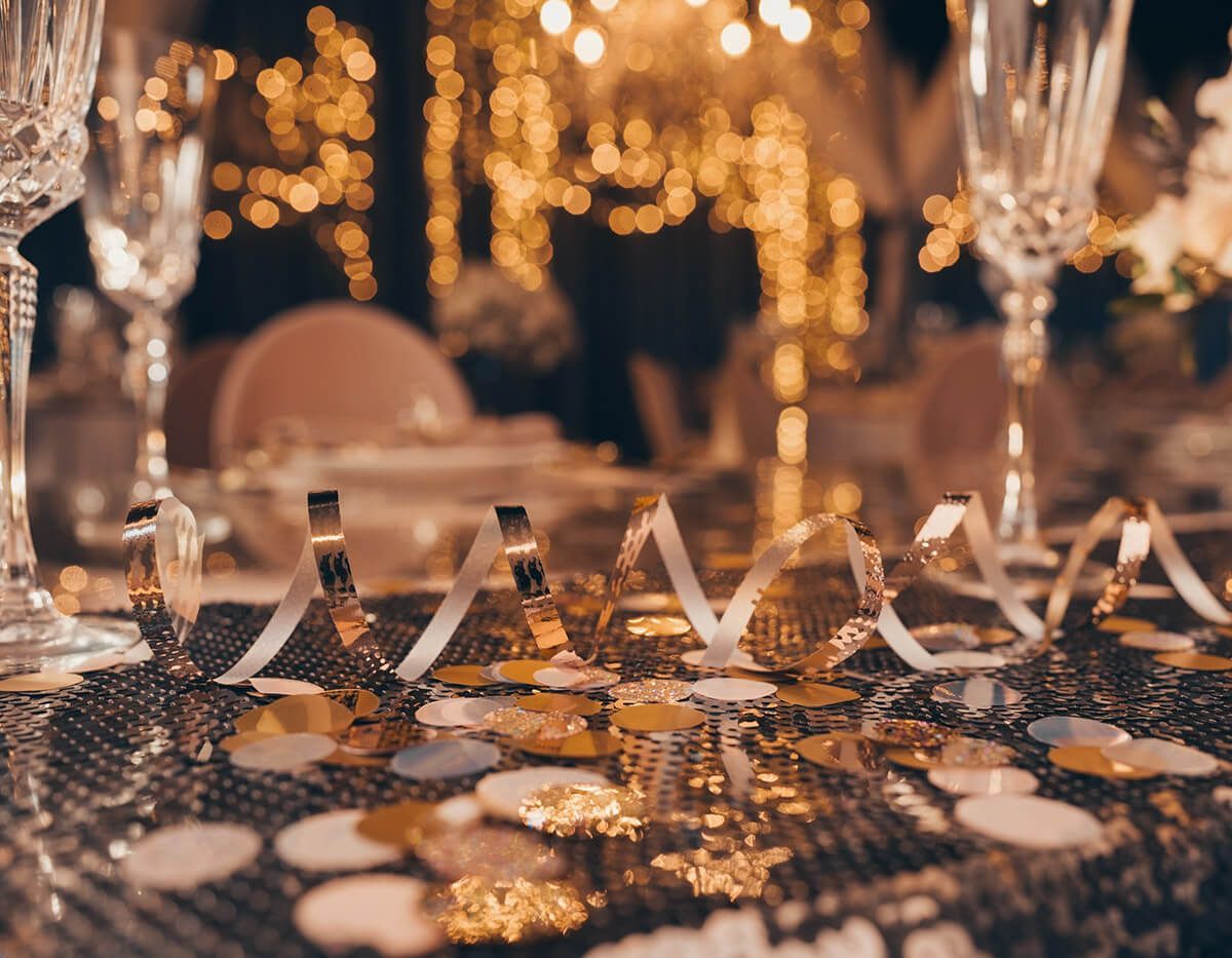 Elegant banquet table with gold decor, champagne flutes, and warm shimmering lights at a formal event