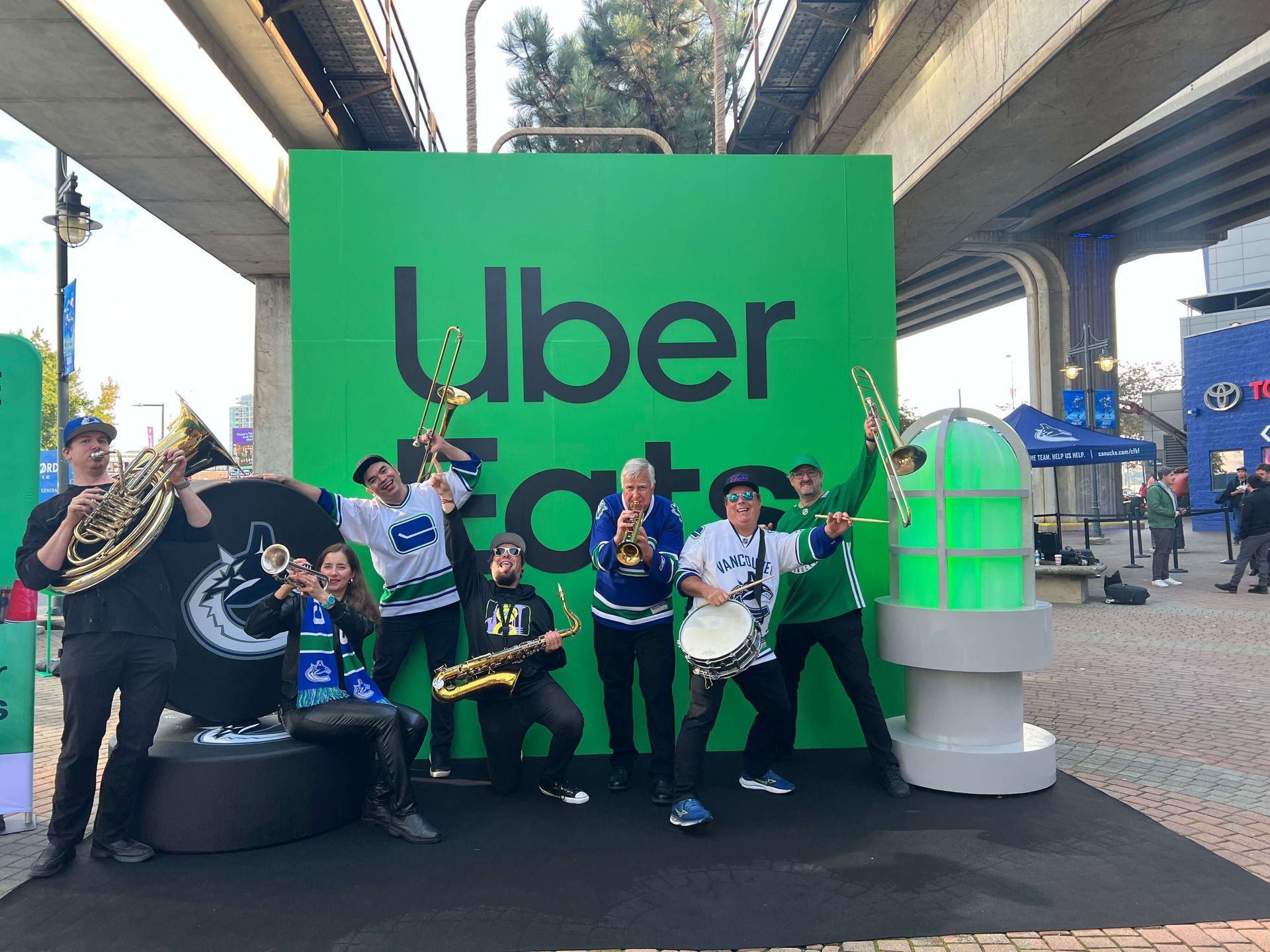 People posing by a large green Uber backdrop with a giant smartphone display in an outdoor plaza