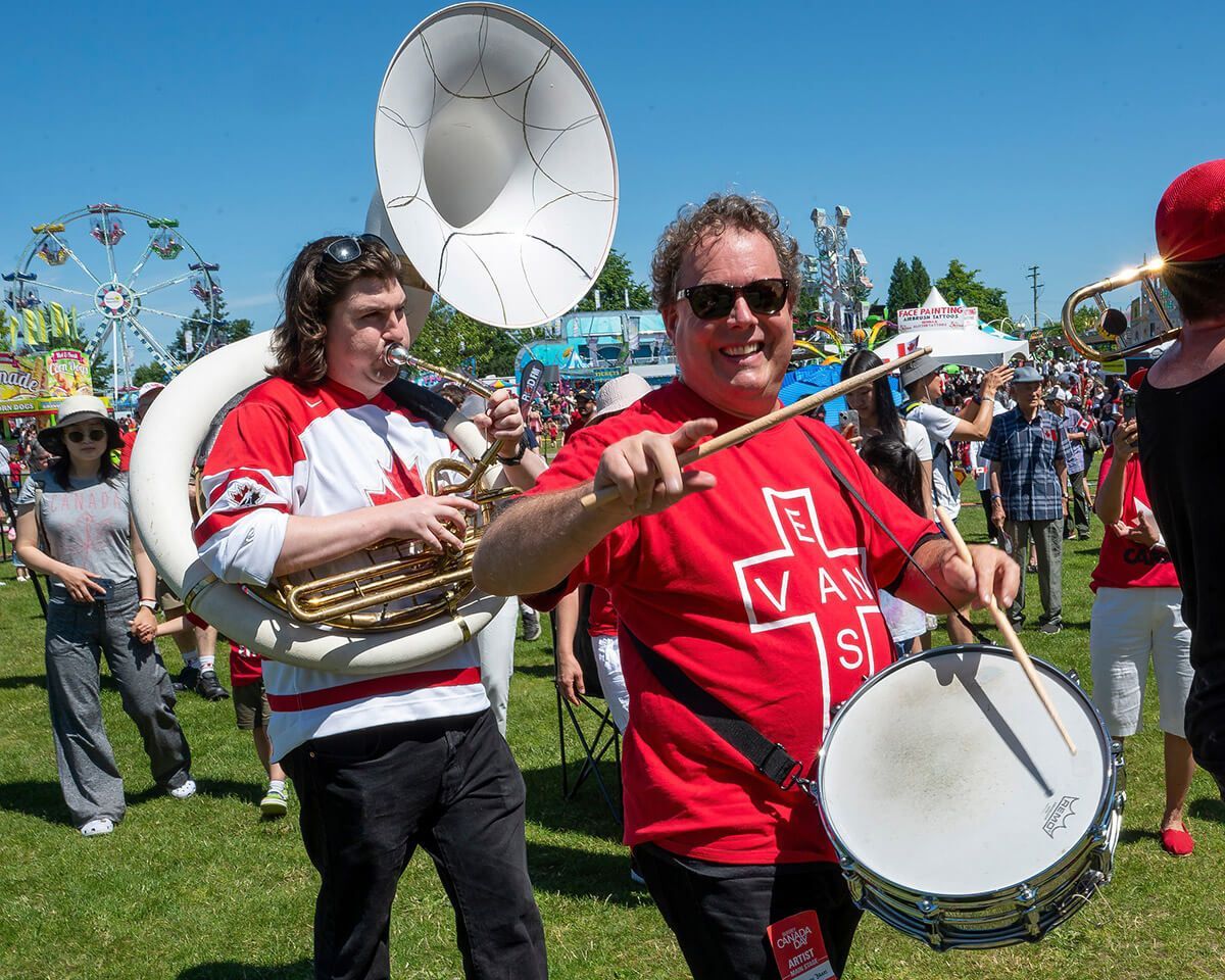 Street musicians playing brass and drum at an outdoor festival on a sunny day