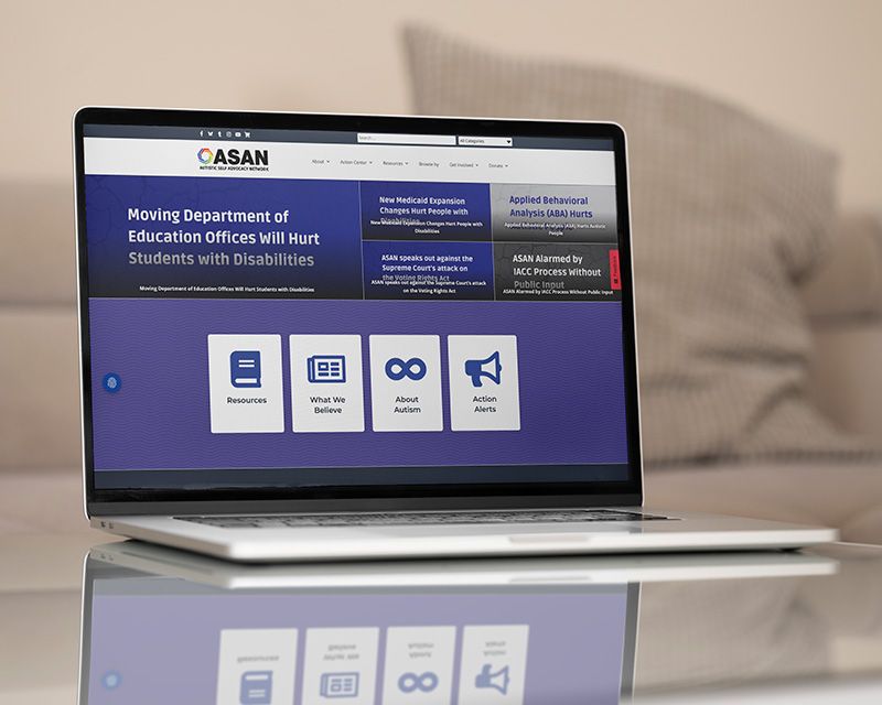 Laptop on a reflective table displaying a website in a bedroom setting