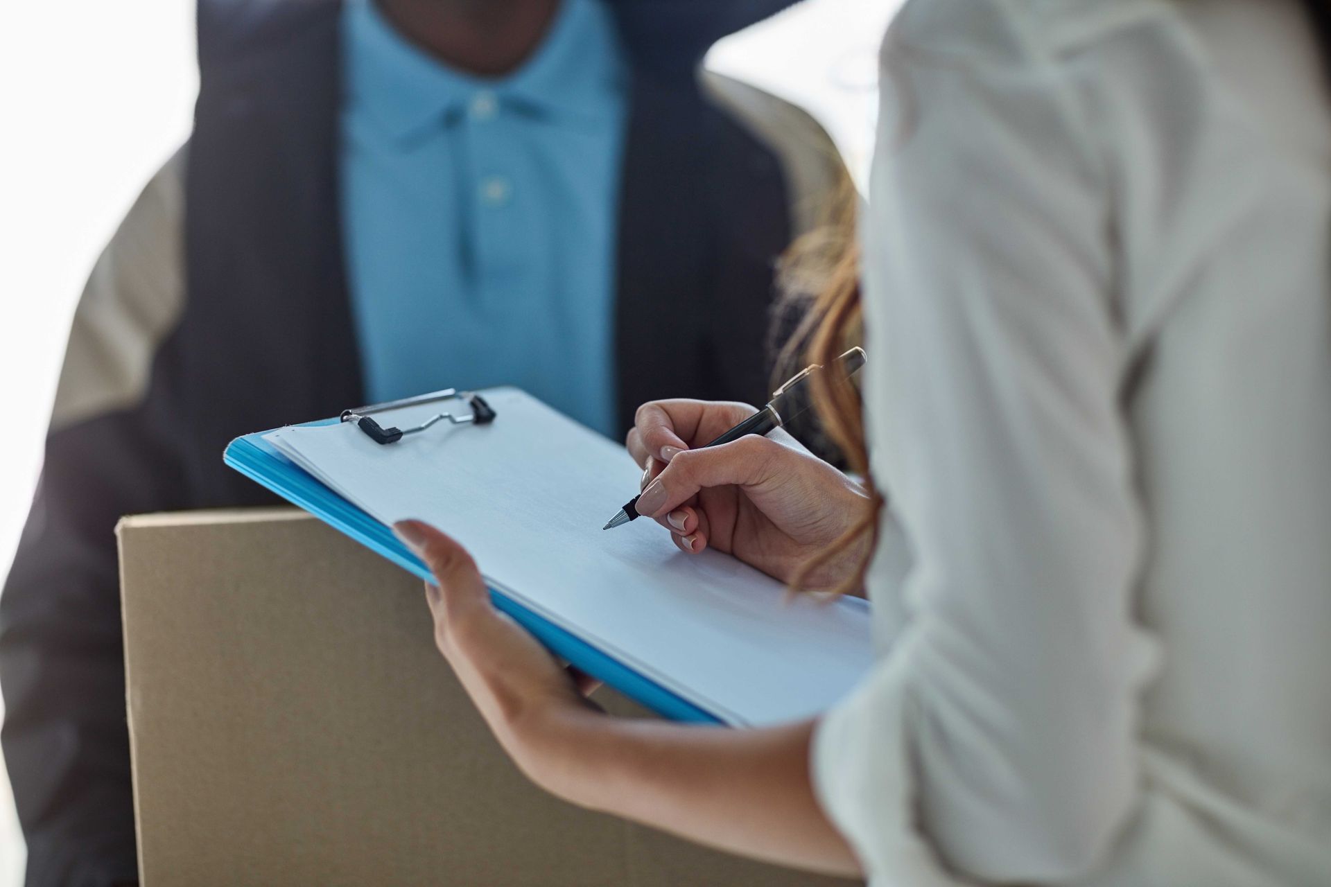 Person taking notes on a clipboard during a meeting