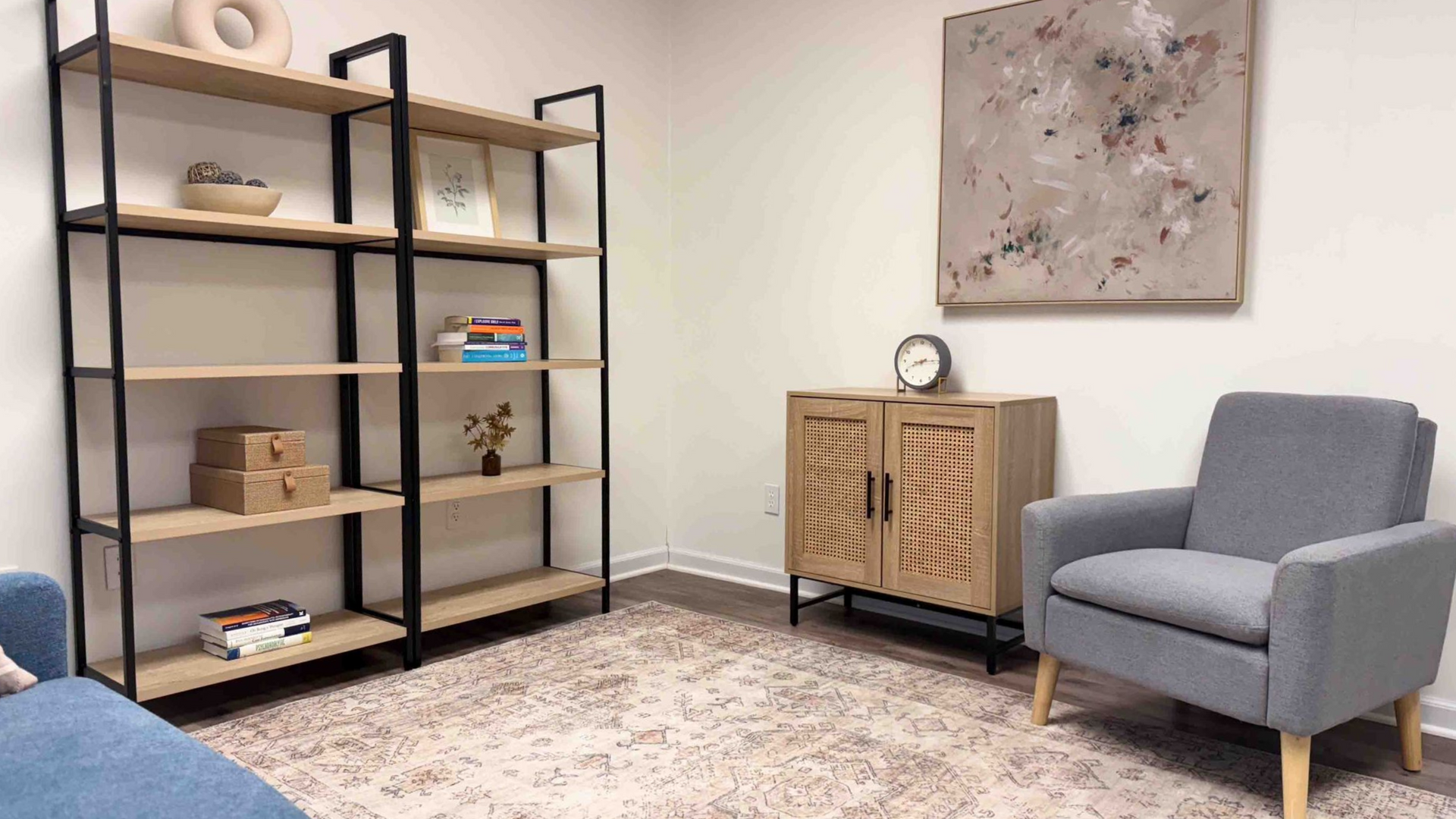 Modern office lounge with shelves, cabinet, wall art, and two gray chairs on a rug