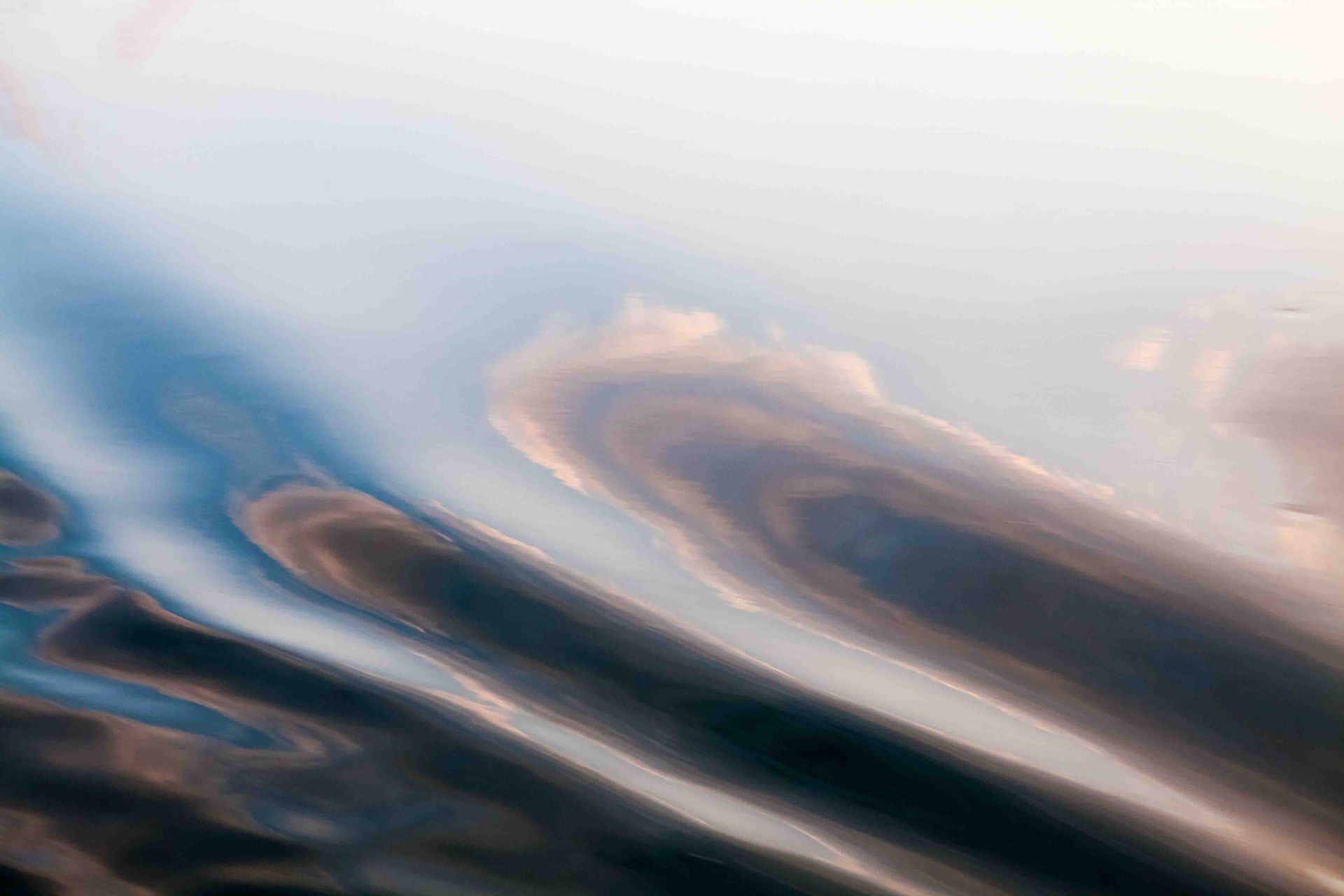 Abstract ripples of blue, gray, and peach clouds or water streaking diagonally across the frame