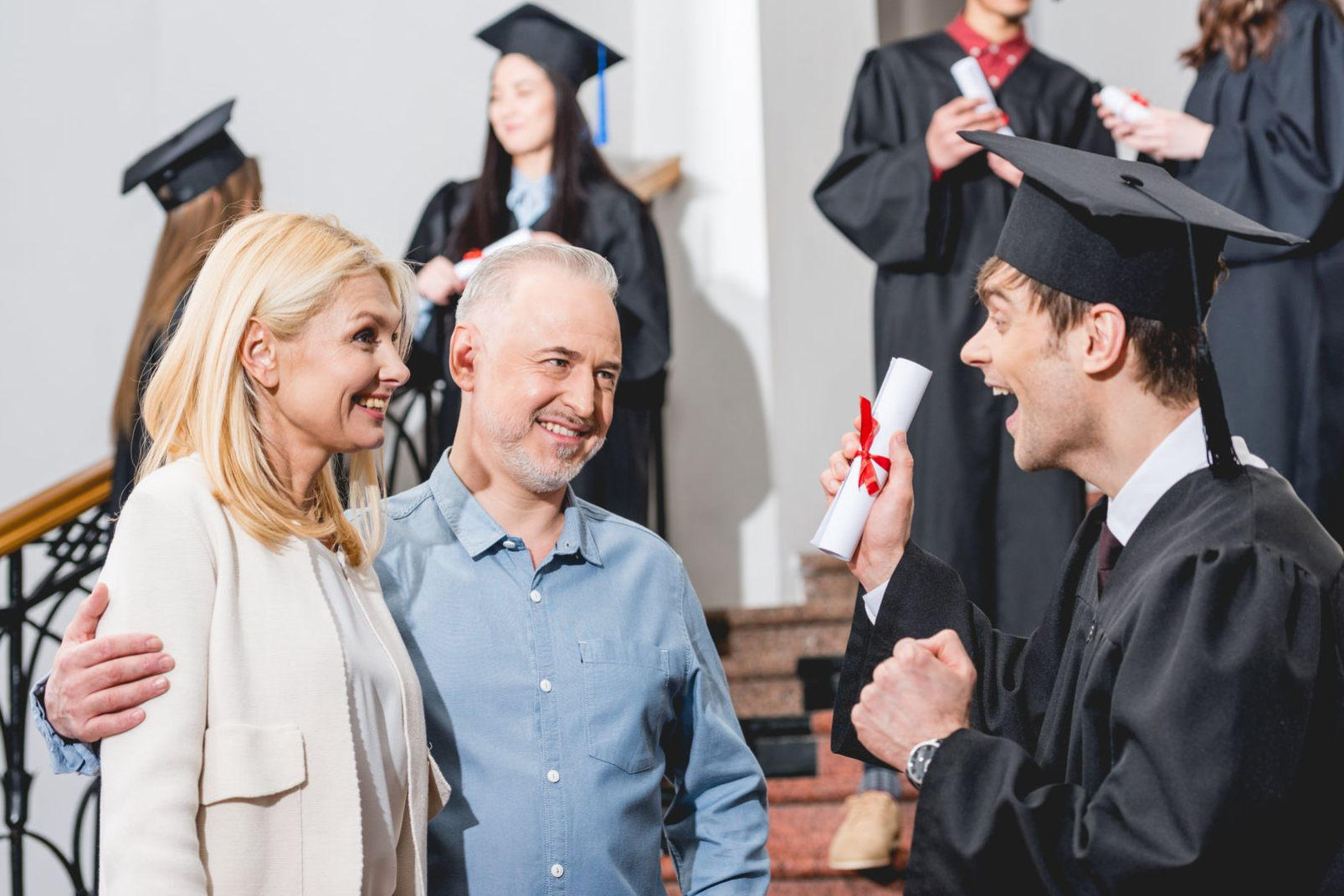 Graduation ceremony with a graduate in cap and gown handing a diploma to smiling family members