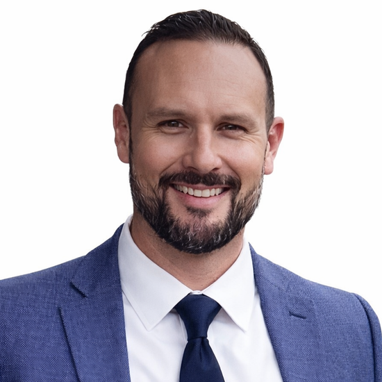 Man in blue suit smiles, headshot.