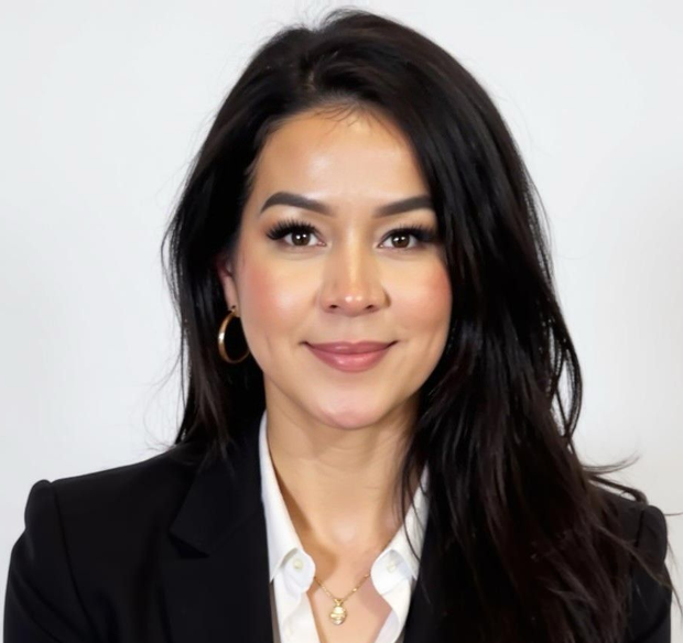 Woman with dark hair, smiling, wearing a white blazer against a white backdrop.