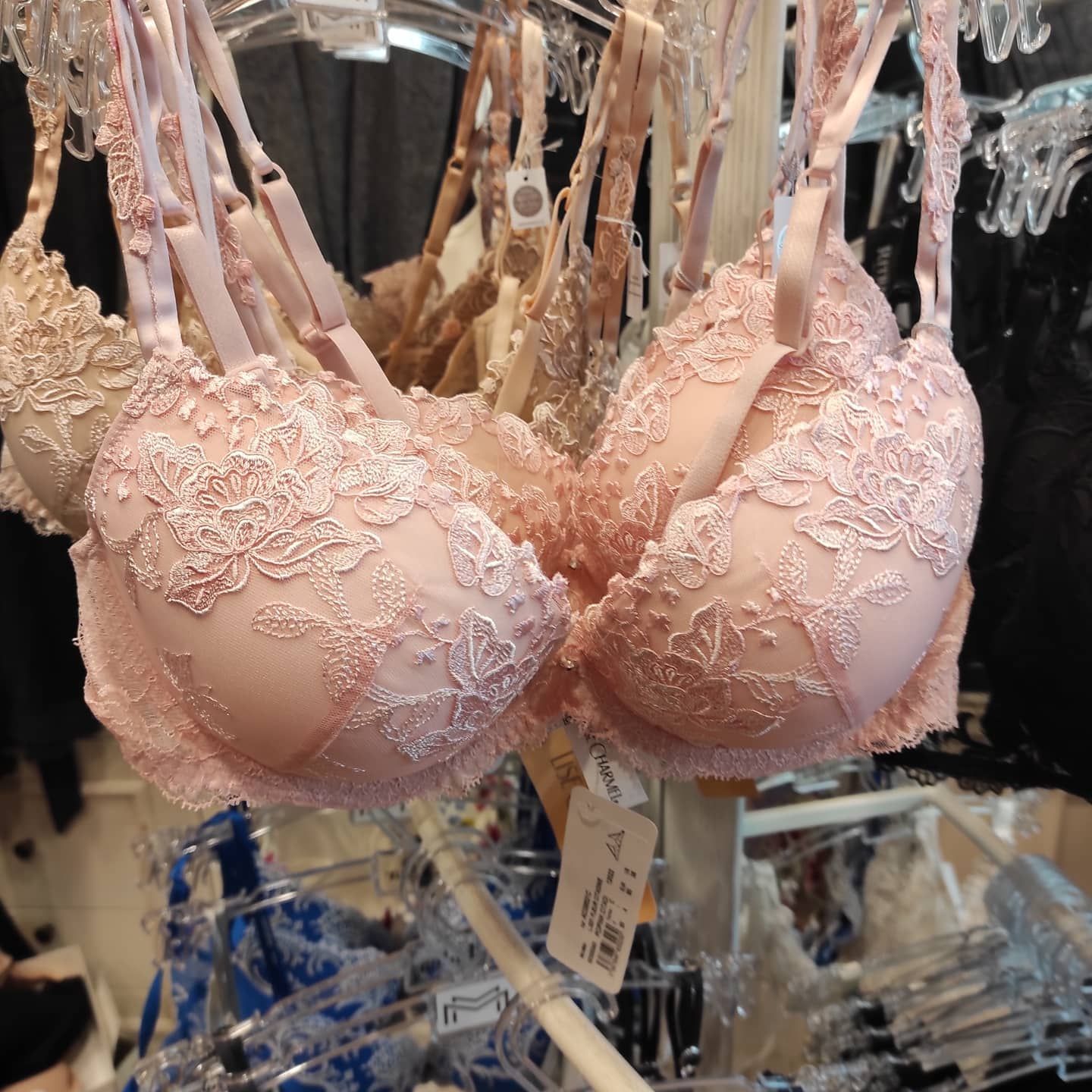 Diversi reggiseni in pizzo rosa appesi a un attaccapanni in un negozio.