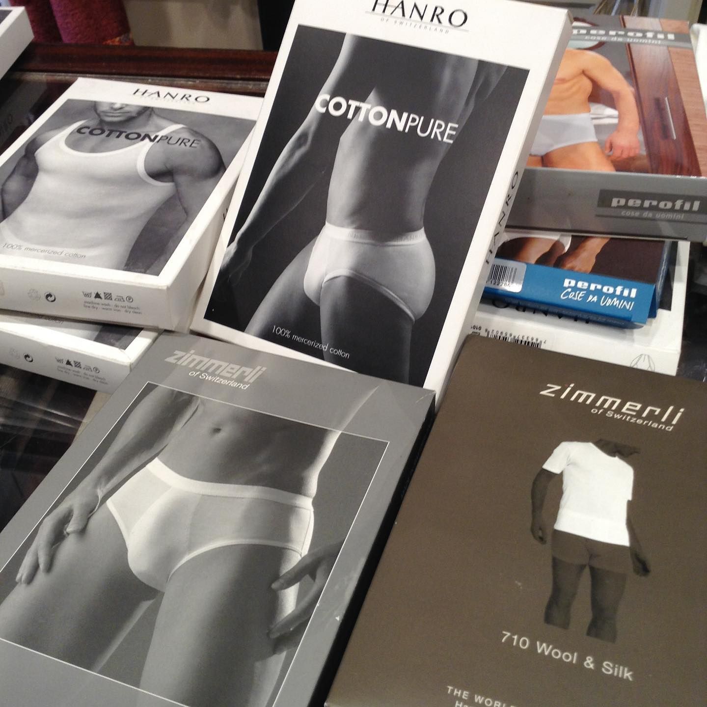 Primo piano delle scatole di biancheria intima con i marchi di abbigliamento maschile: Hanro, Zimmerli e Beretti.