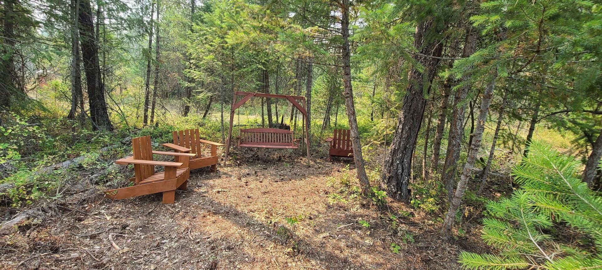 Woodland picnic area with wooden benches and a fire pit among trees and greenery