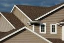 Brown roofed house with white trim, tan siding, and two windows.