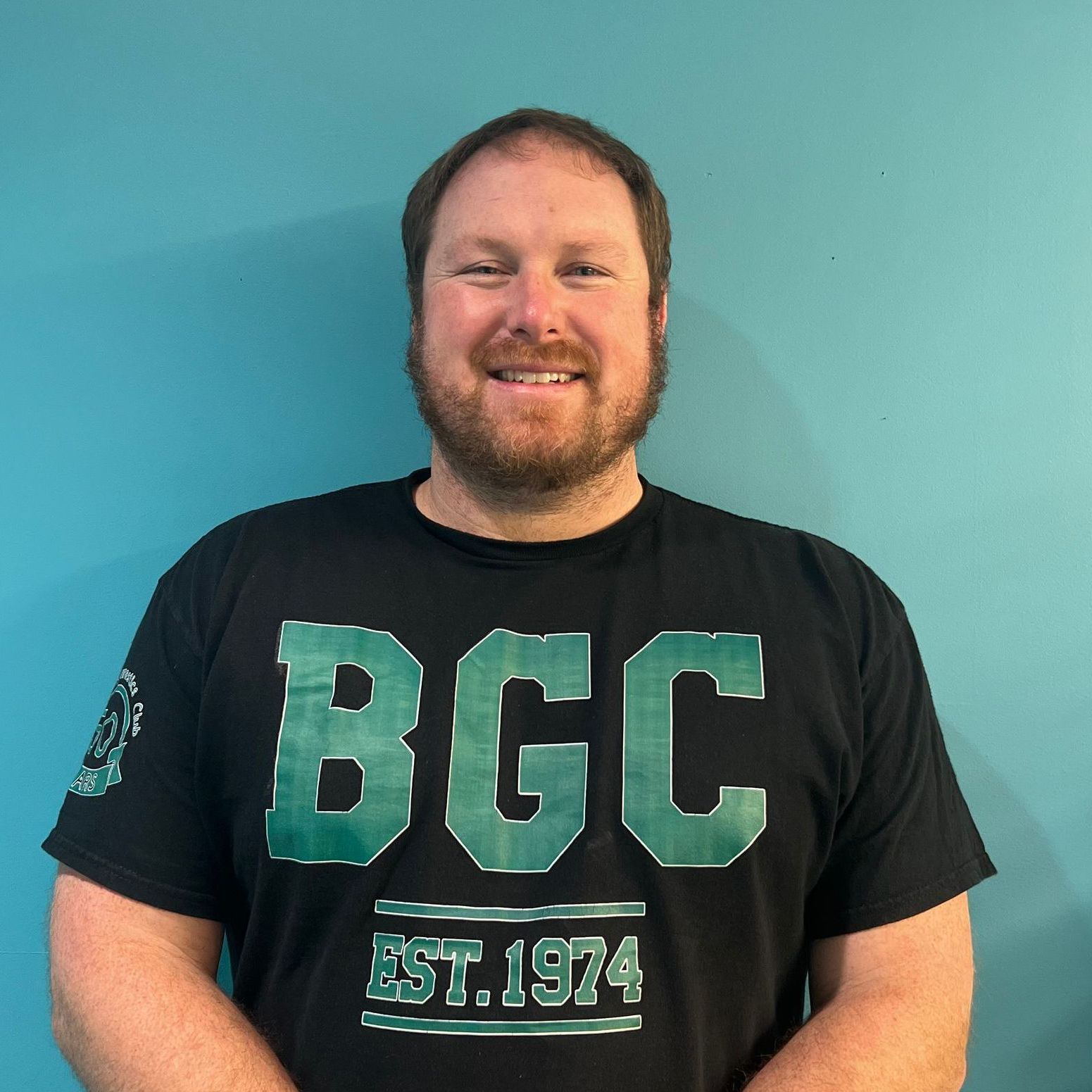A man is wearing a black t-shirt with the word bcc on it.
