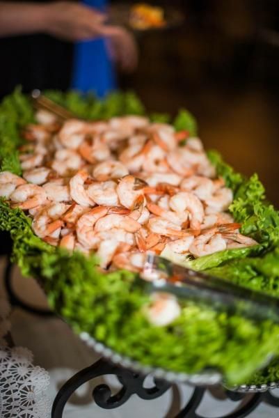 A tray of shrimp on lettuce with tongs on a table.