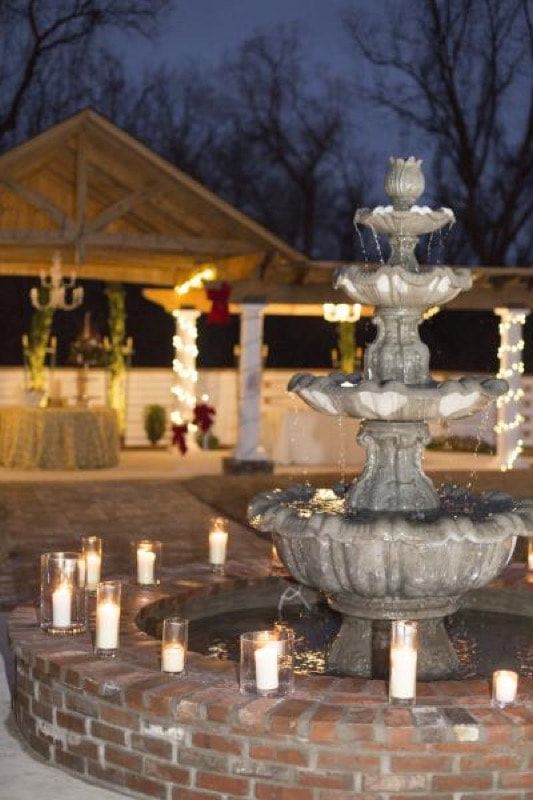 A fountain with candles around it and a gazebo in the background