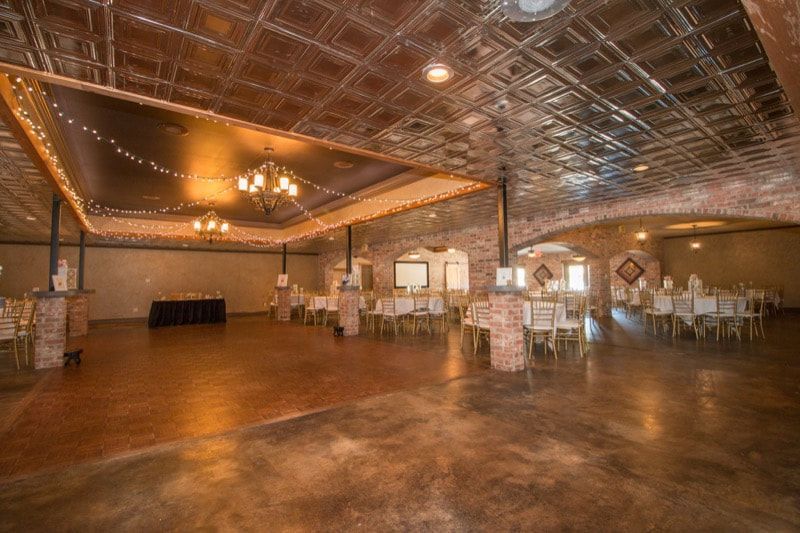 A large empty room with tables and chairs and a dance floor.