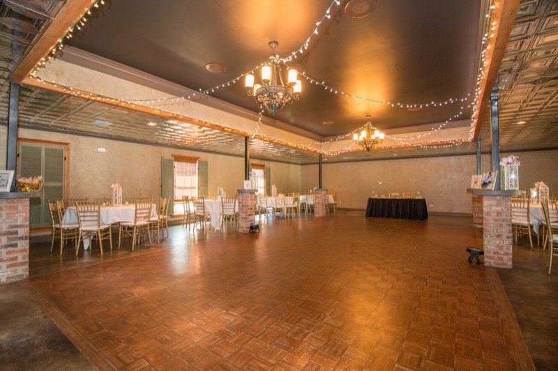 A large empty room with a wooden floor and tables and chairs.