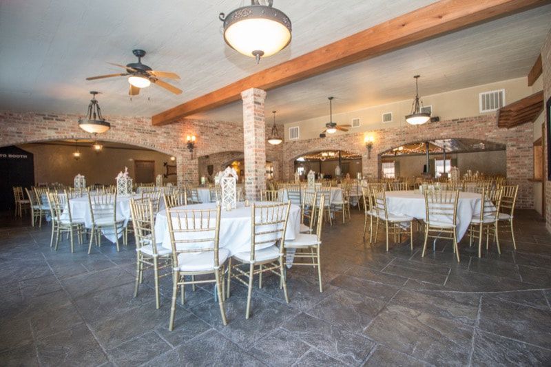A large room with tables and chairs set up for a wedding reception.