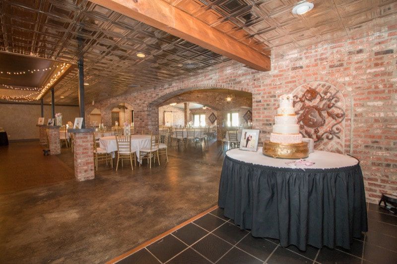 A wedding cake is sitting on top of a table in a large room.