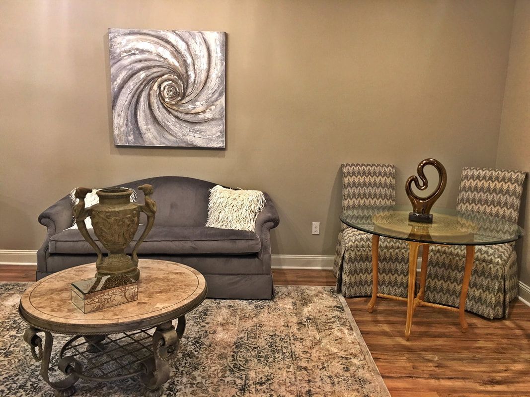 A living room with a couch , table , chairs and a painting on the wall.