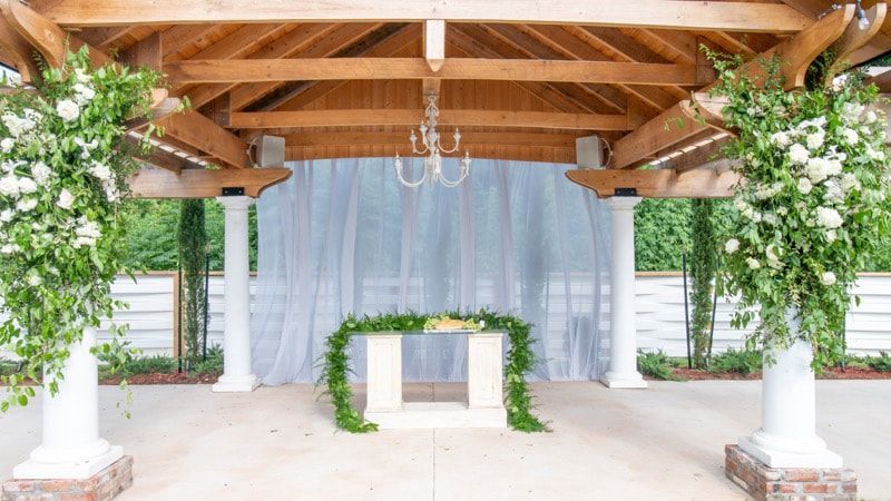 There is a table under a gazebo with flowers on it.