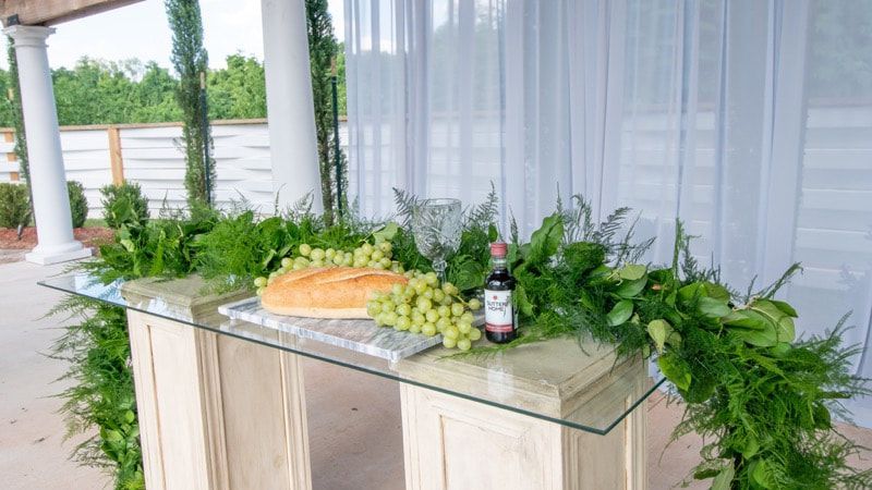 A table with a bottle of wine , grapes and bread on it.
