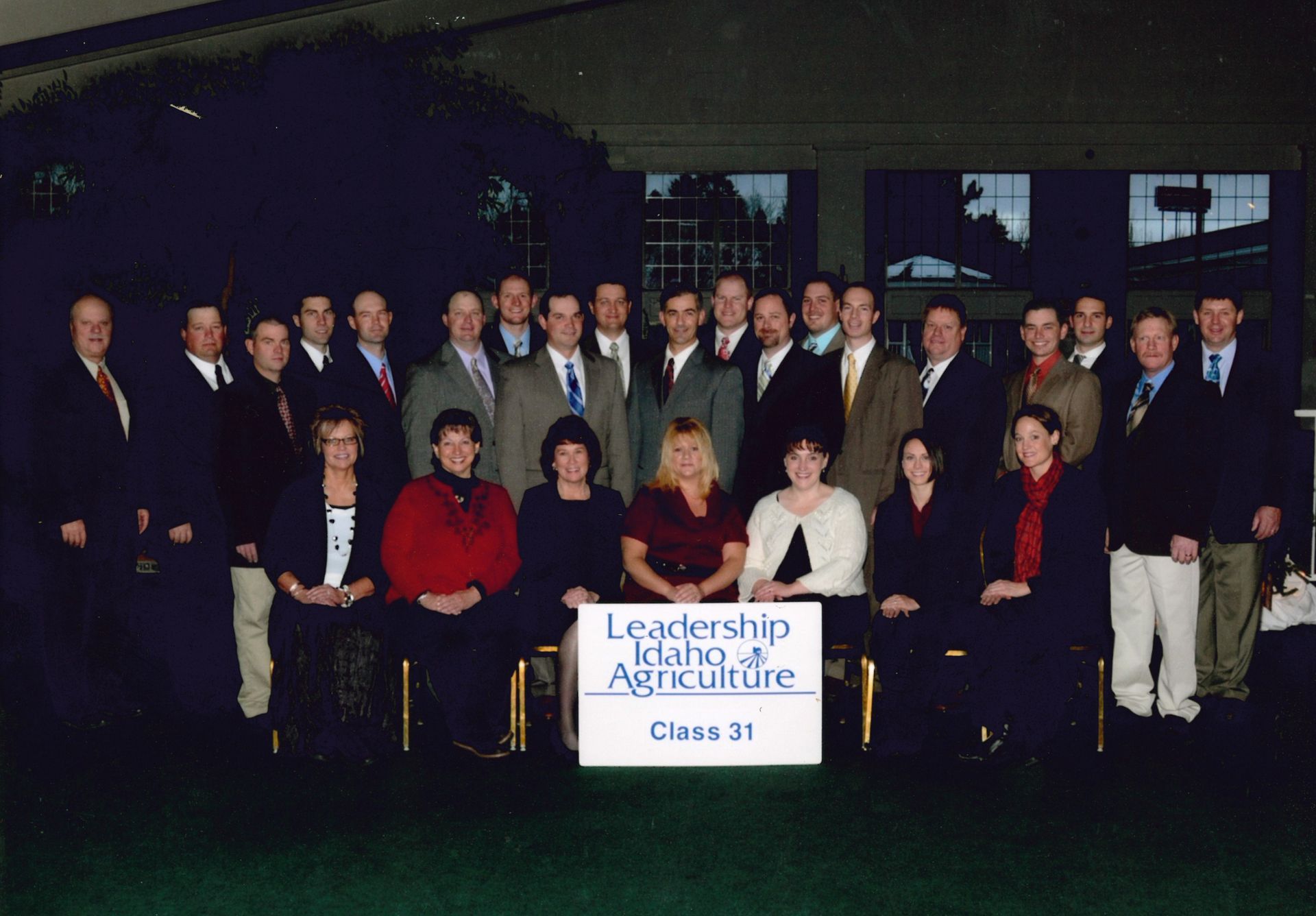 A group of professionals in business attire pose behind a sign that reads