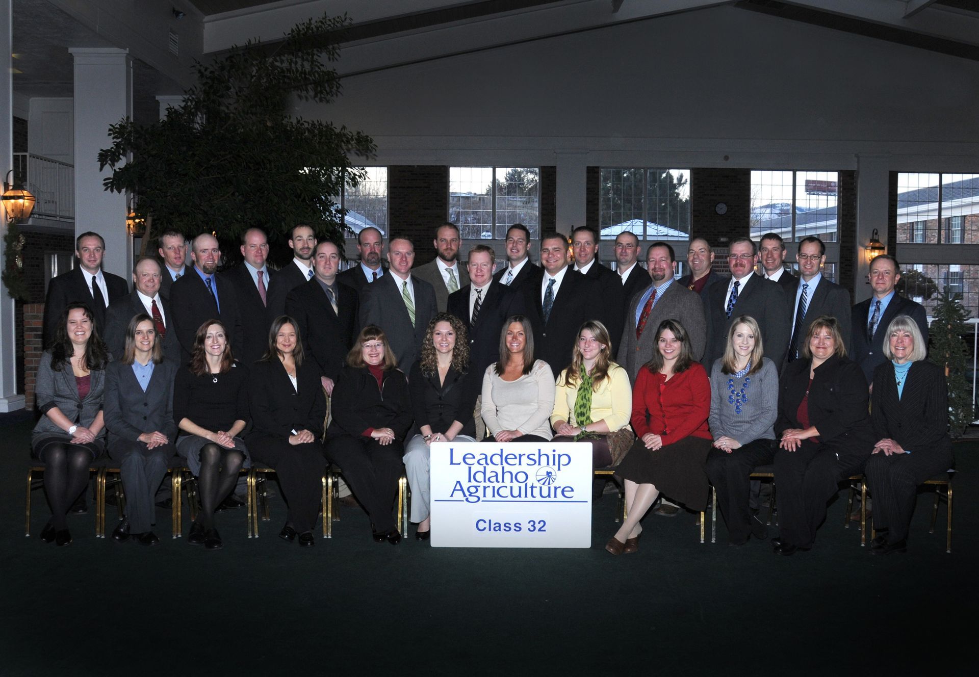 A group poses in a dimly lit, professional setting behind a sign that reads