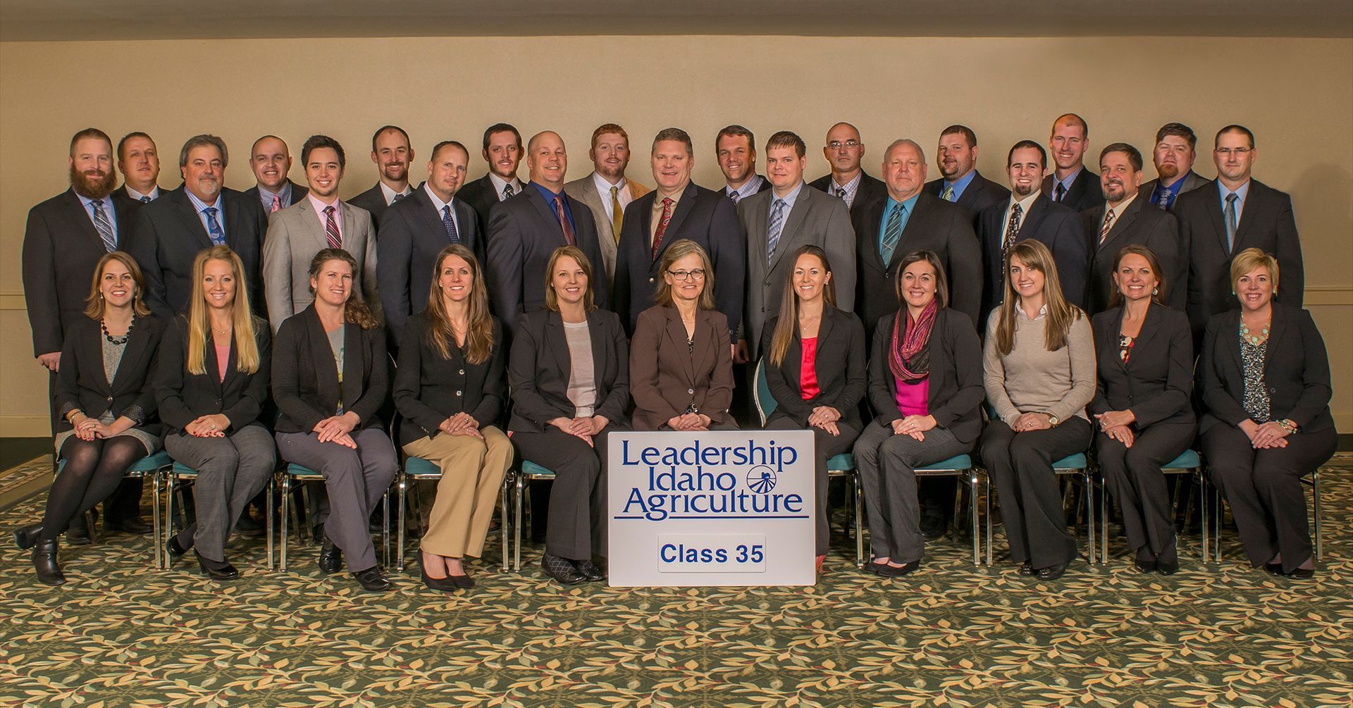 A group of people standing and sitting together behind a sign that reads