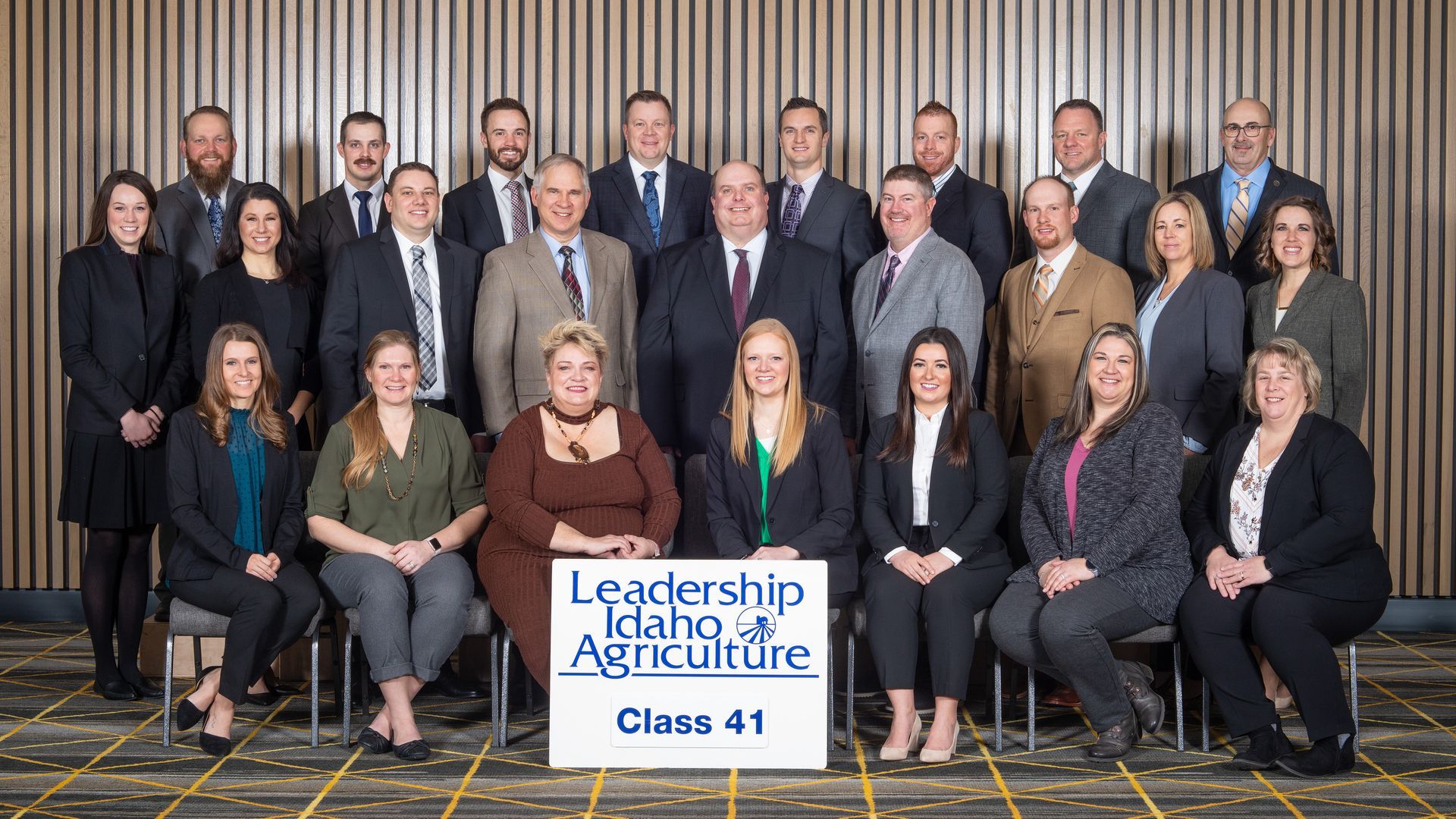 Group photo of the Leadership Idaho Agriculture Class 41 cohort posing in front of a wood-paneled wall.